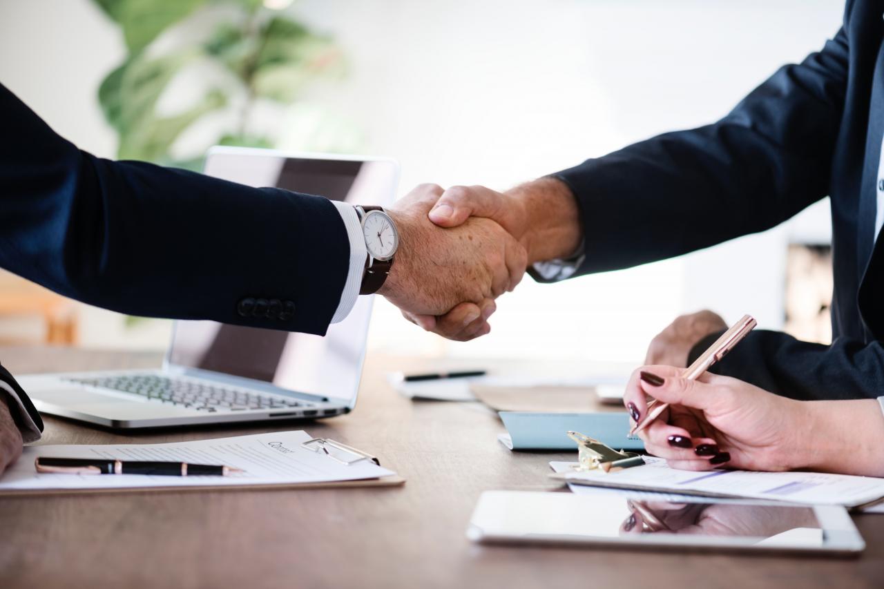 Two people shaking hands over paperwork